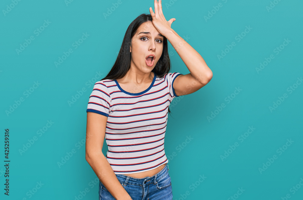 Young hispanic girl wearing casual striped t shirt surprised with hand on head for mistake, remember error. forgot, bad memory concept. Young hispanic girl wearing casual striped t shirt surprised with hand on head for mistake, remember error. forgot, bad memory concept.