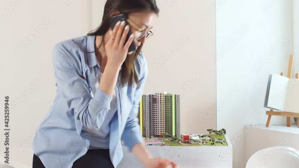 professional designer is talking on the phone in the office, a woman is negotiating with clients using a smartphone in her office professional designer is talking on the phone in the office, a woman is negotiating with clients using a smartphone in her office