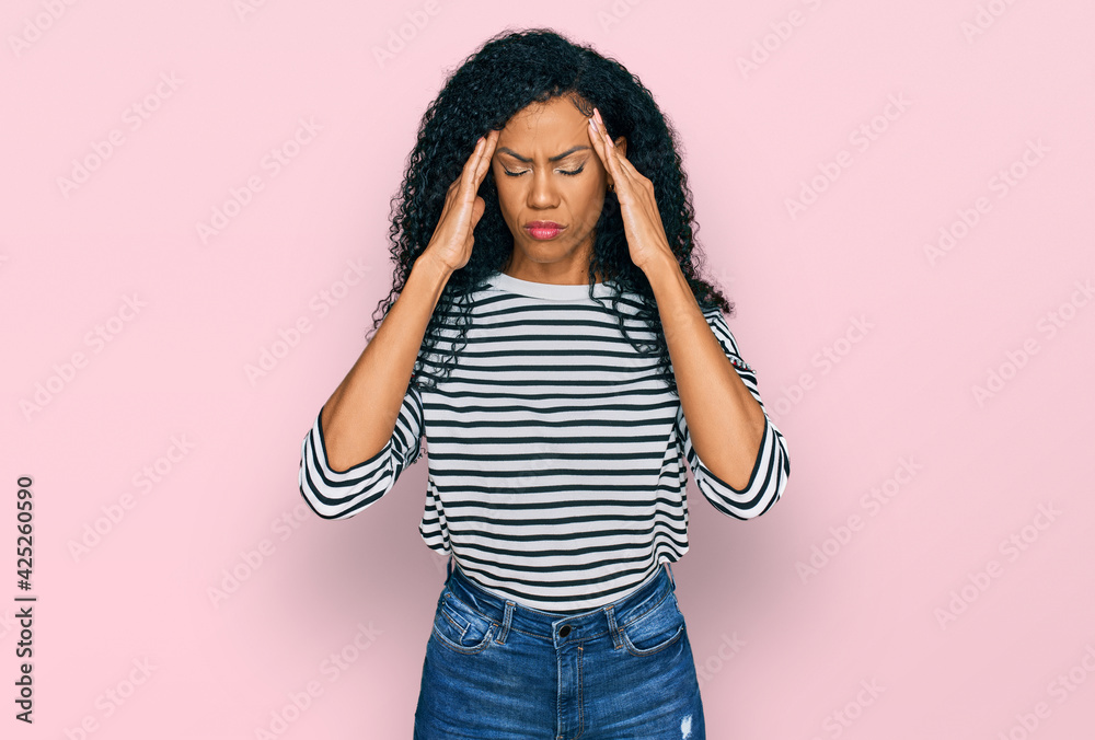 Middle age african american woman wearing casual clothes with hand on head for pain in head because stress. suffering migraine. Middle age african american woman wearing casual clothes with hand on head for pain in head because stress. suffering migraine.