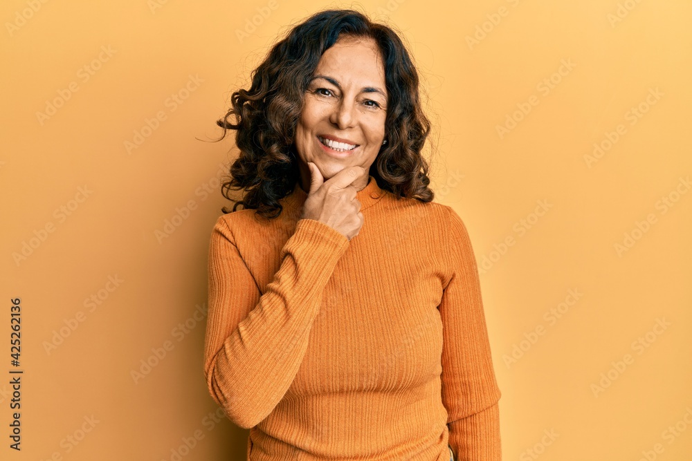 Middle age hispanic woman wearing casual clothes looking confident at the camera smiling with crossed arms and hand raised on chin. thinking positive. Middle age hispanic woman wearing casual clothes looking confident at the camera smiling with crossed arms and hand raised on chin. thinking positive.