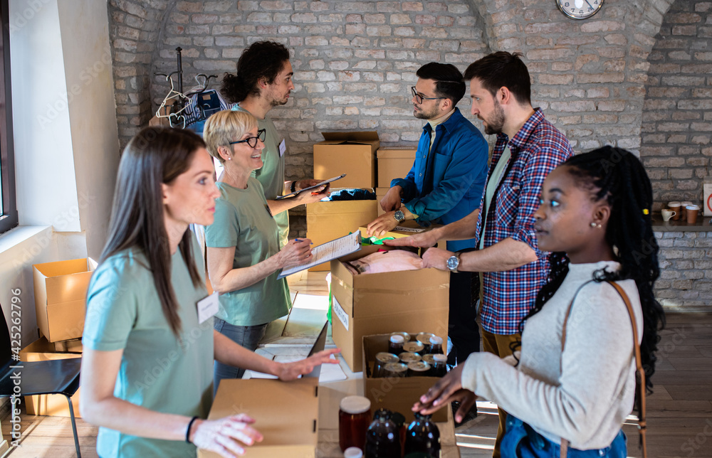 Group of volunteers with working in community charity donation center.