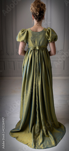 A young Regency woman wearing a green shot silk dress and viewed from behind