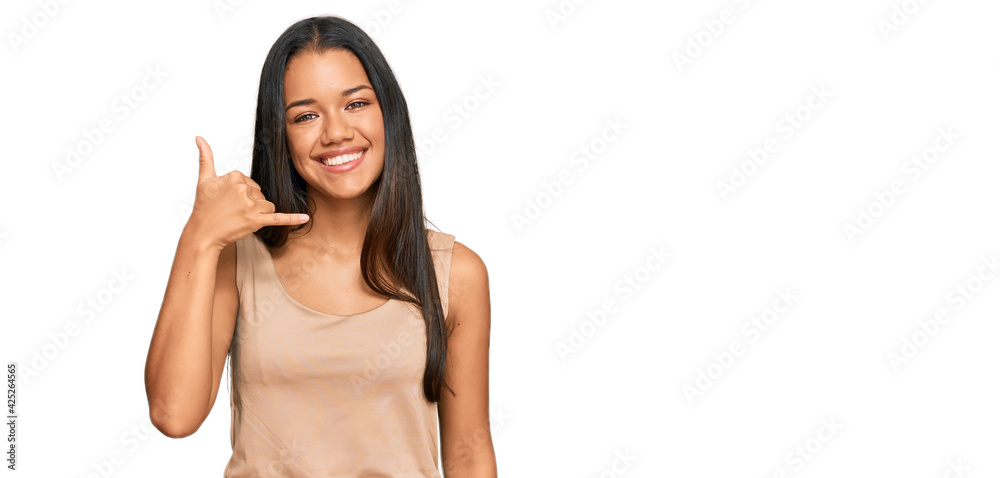 Beautiful hispanic woman wearing casual clothes smiling doing phone gesture with hand and fingers like talking on the telephone. communicating concepts. Beautiful hispanic woman wearing casual clothes smiling doing phone gesture with hand and fingers like talking on the telephone. communicating concepts.