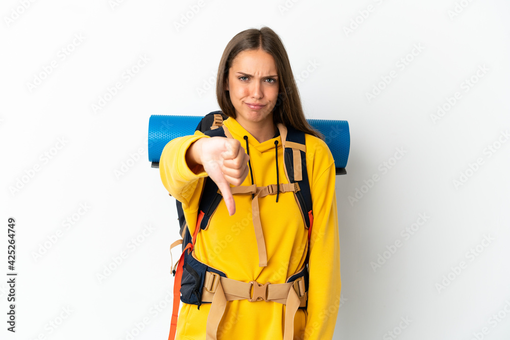 Young mountaineer woman with a big backpack over isolated white background showing thumb down with negative expression Young mountaineer woman with a big backpack over isolated white background showing thumb down with negative expression