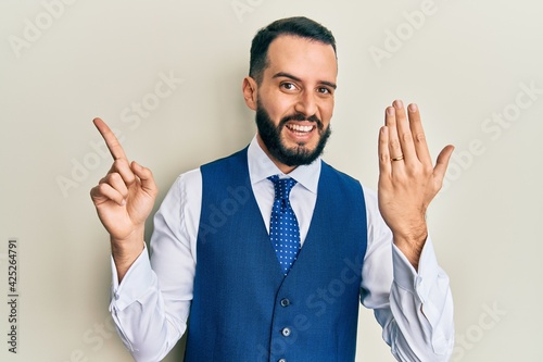 Young man with beard wearing engagement ring smiling happy pointing with hand and finger to the side