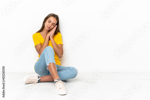 Young girl sitting on the floor making sleep gesture in dorable expression
