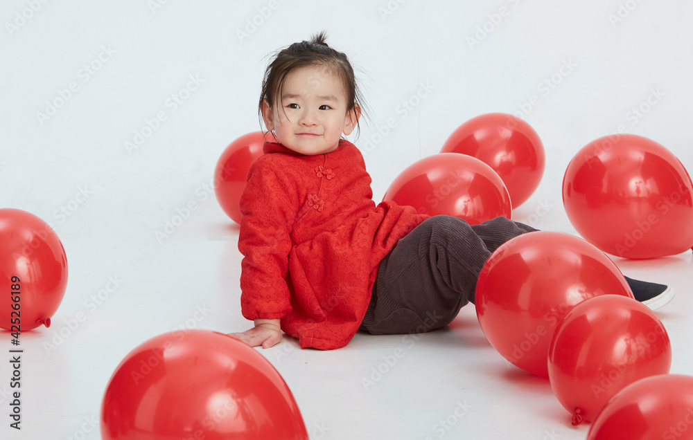 Cute Asian little girl playing with festive red balloons. Wearing traditional Chinese New Year costumes Cute Asian little girl playing with festive red balloons. Wearing traditional Chinese New Year costumes