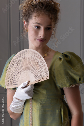 Canvas Print A young Regency woman wearing a green shot silk dress and satin gloves and holdi