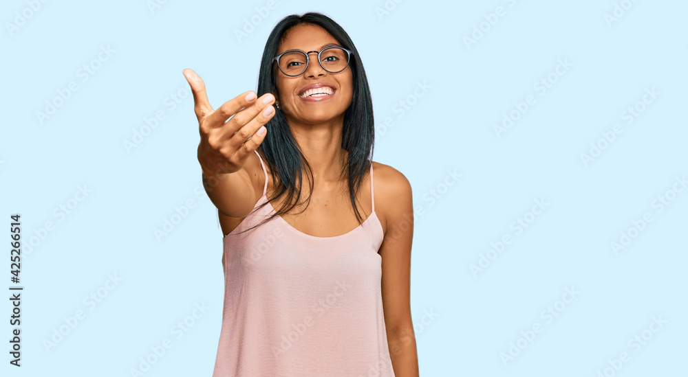Young african american woman wearing casual clothes and glasses smiling friendly offering handshake as greeting and welcoming. successful business. Young african american woman wearing casual clothes and glasses smiling friendly offering handshake as greeting and welcoming. successful business.