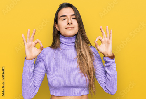 Young hispanic woman wearing casual clothes relaxed and smiling with eyes closed doing meditation gesture with fingers. yoga concept.