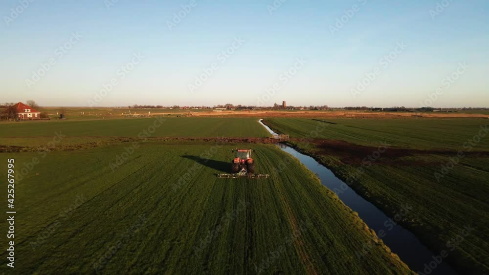 Tractor at a farm on a grass land at sunset aerial drone cinematic footage. Tractor at a farm on a grass land at sunset aerial drone cinematic footage.