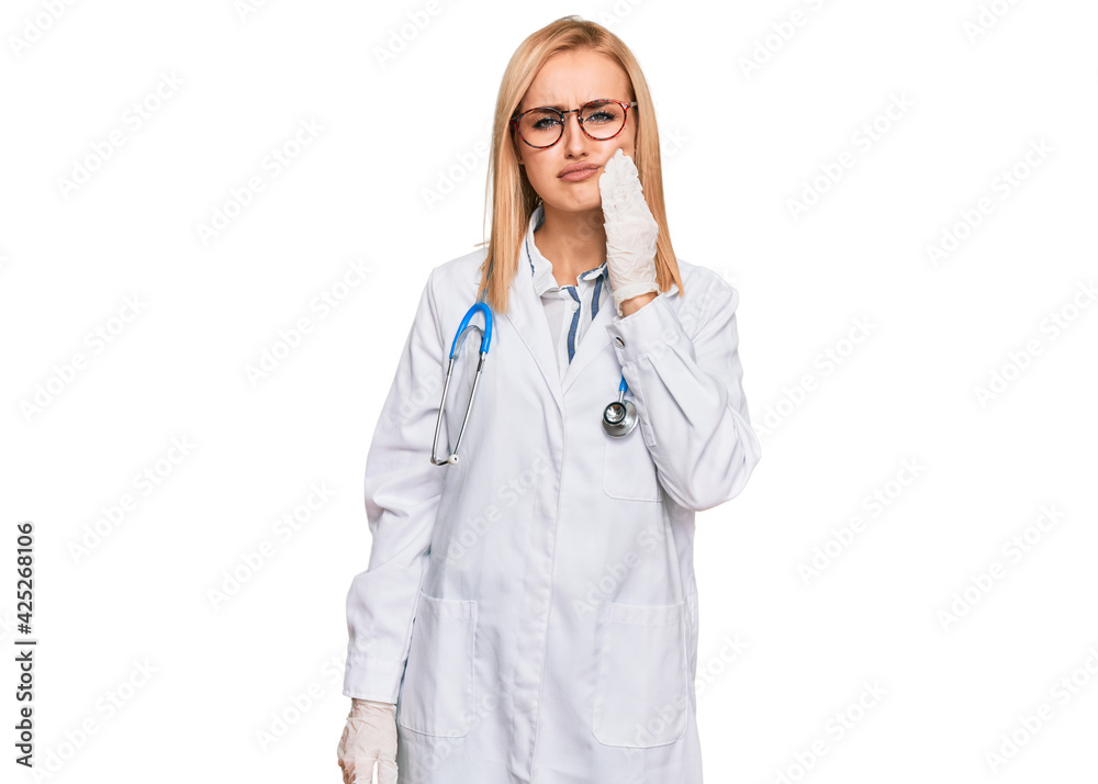 Beautiful caucasian woman wearing doctor uniform and stethoscope touching mouth with hand with painful expression because of toothache or dental illness on teeth. dentist Beautiful caucasian woman wearing doctor uniform and stethoscope touching mouth with hand with painful expression because of toothache or dental illness on teeth. dentist