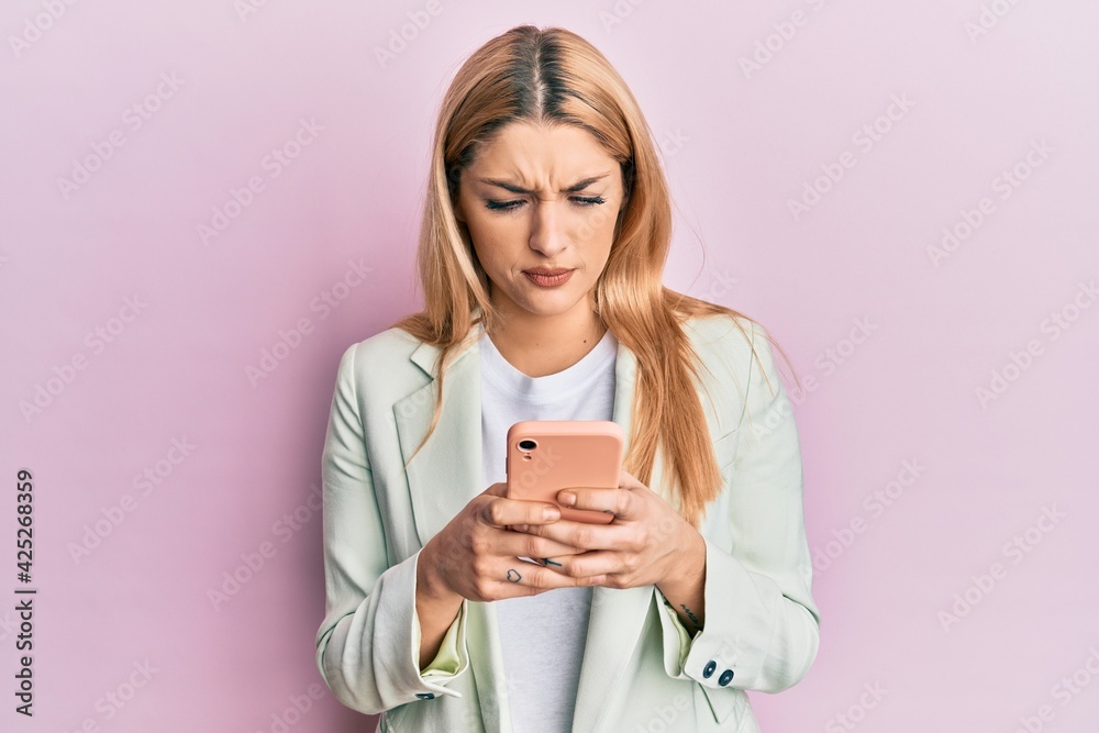 Young caucasian woman wearing business clothes using smartphone skeptic and nervous, frowning upset because of problem. negative person. Young caucasian woman wearing business clothes using smartphone skeptic and nervous, frowning upset because of problem. negative person.