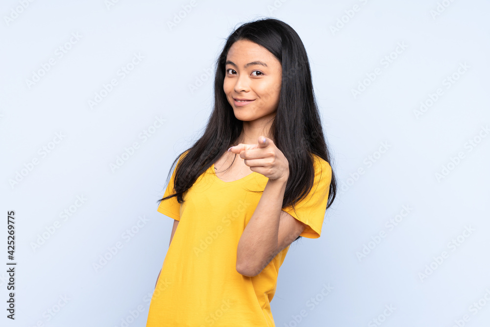 Teenager Chinese woman isolated on blue background surprised and pointing front Teenager Chinese woman isolated on blue background surprised and pointing front