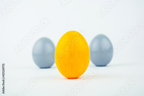 Three easter trendy decorated eggs yellow and gray stand on a white background Minimal easter style