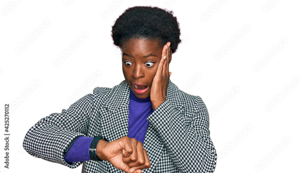 Young african american girl wearing casual clothes looking at the watch time worried, afraid of getting late Young african american girl wearing casual clothes looking at the watch time worried, afraid of getting late