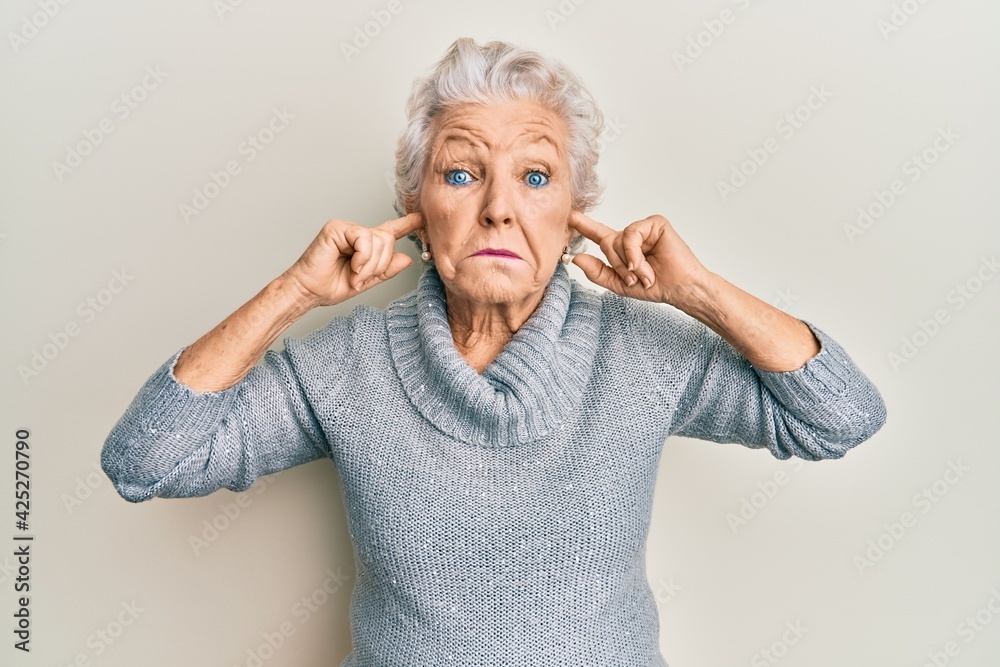 Senior grey-haired woman covering ears with finger clueless and confused expression. doubt concept. Senior grey-haired woman covering ears with finger clueless and confused expression. doubt concept.