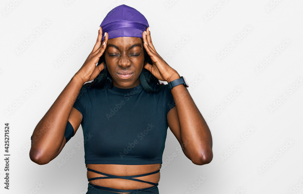 Young african american woman wearing sportswear suffering from headache desperate and stressed because pain and migraine. hands on head. Young african american woman wearing sportswear suffering from headache desperate and stressed because pain and migraine. hands on head.