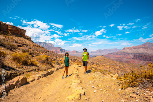 A young couple in a green shirt resting with the great canyon in the background, on the South Kaibab Trailhead trek. Grand canyon.
