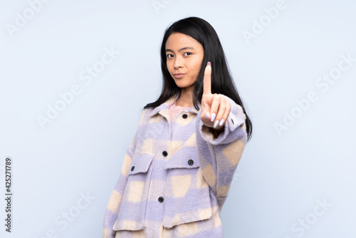 Teenager Chinese woman isolated on blue background counting one with serious expression © luismolinero