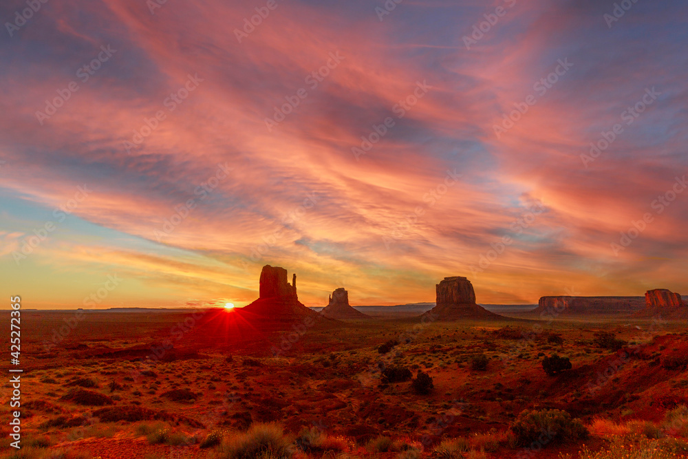 Red sunrise and its first sunbeams in the beautiful Monument Valley, Utah.
