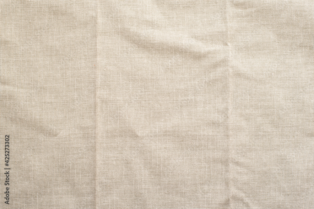 Beige natural linen fabric with folds close up Beige natural linen fabric with folds close up