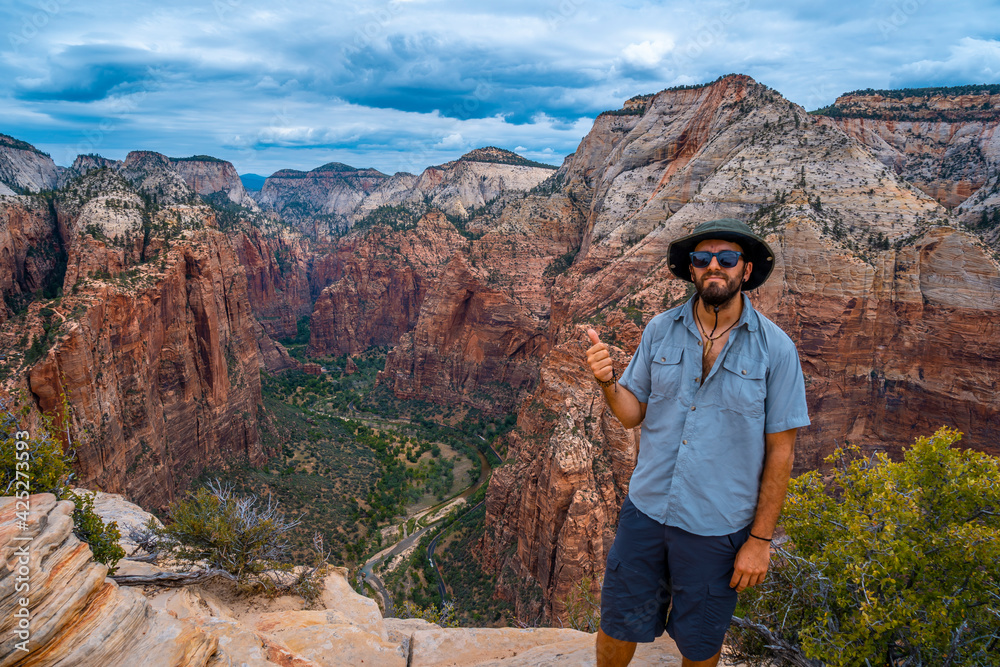 Naklejka premium A young man enjoying the views of Zion from the Angels Landing Trail in Zion National Park, Utah. United States.