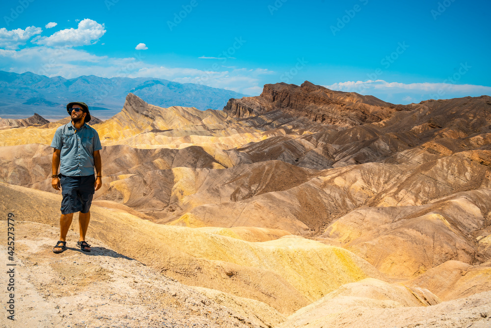 A man with a green shirt on the beautiful viewpoint of Zabriskre Point, California. United States.