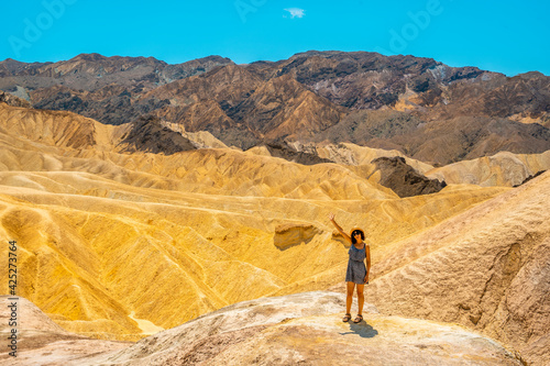 A young woman in dress enjoying the view of the viewpoint of Zabriskie Point, California. United States.