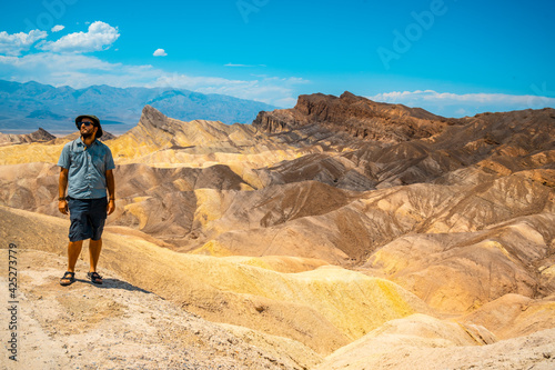 A man with a green shirt on the beautiful viewpoint of Zabriskre Point  California. United States.