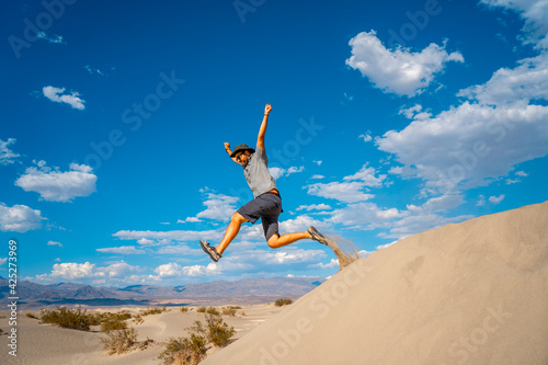 A young man in a blue shirt taking a leap in the desert of Death Valley, California. USA