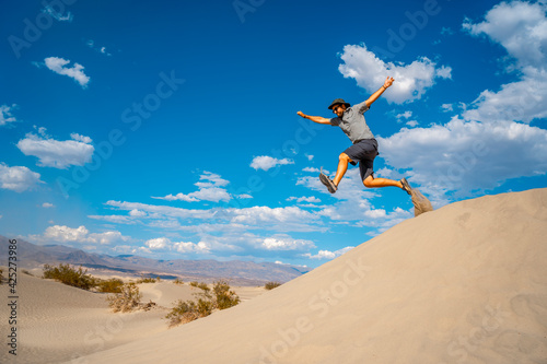 A young man in a blue shirt taking a leap in the desert of Death Valley, California. USA