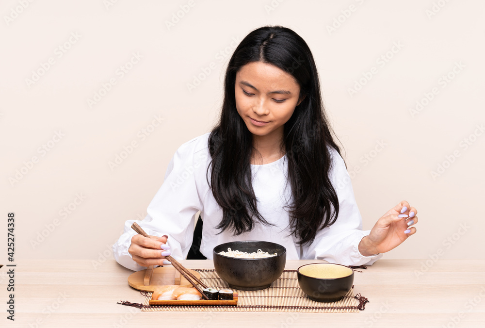 Teenager Asian girl eating asian food isolated on beige background Teenager Asian girl eating asian food isolated on beige background