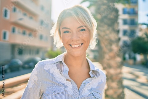 Young blonde woman smiling happy walking at the park.