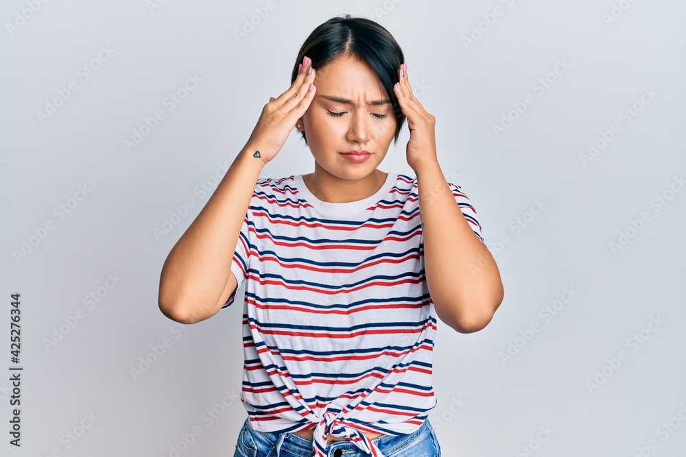 Beautiful young woman with short hair wearing casual clothes suffering from headache desperate and stressed because pain and migraine. hands on head. Beautiful young woman with short hair wearing casual clothes suffering from headache desperate and stressed because pain and migraine. hands on head.