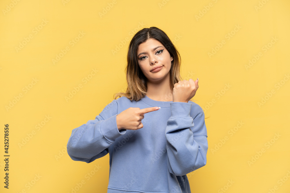Young Russian girl isolated on yellow background making the gesture of being late Young Russian girl isolated on yellow background making the gesture of being late