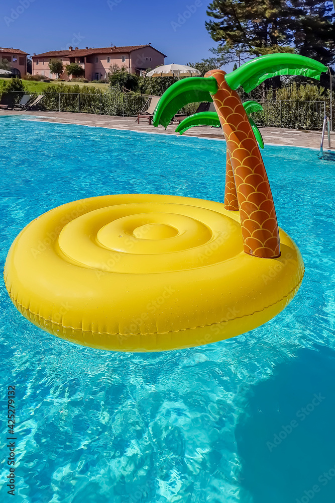 An inflatable in the shape of a desert island with palm trees floats in