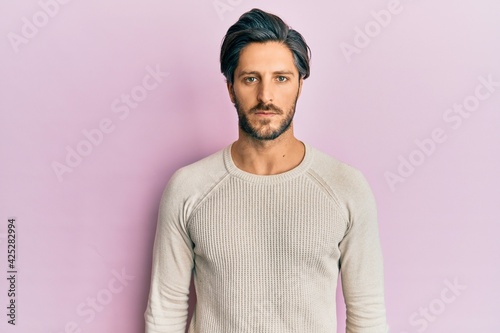 Young hispanic man wearing casual winter sweater relaxed with serious expression on face. simple and natural looking at the camera.