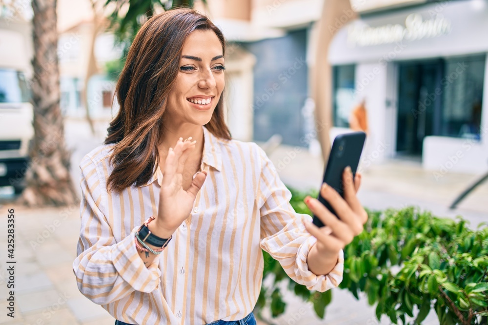 Young hispanic woman smiling happy doing video call using smartphone at the city. Young hispanic woman smiling happy doing video call using smartphone at the city.