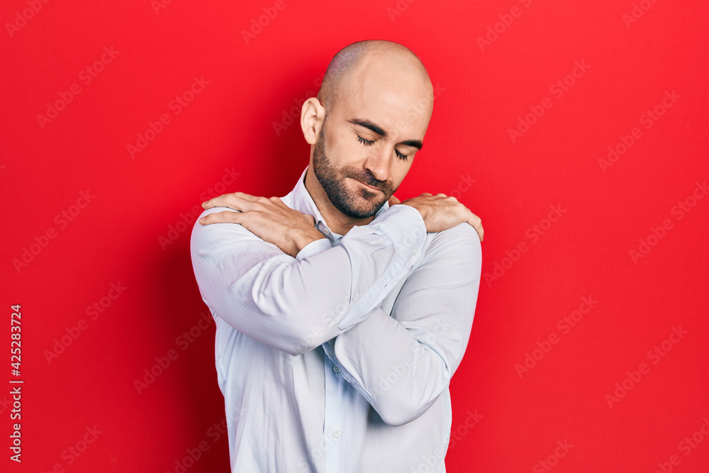Young bald man wearing elegant clothes hugging oneself happy and positive, smiling confident. self love and self care