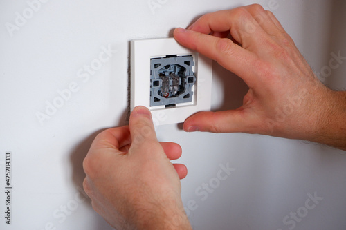A man repairs a lighting switch. Close-up on hand. Electrician work.