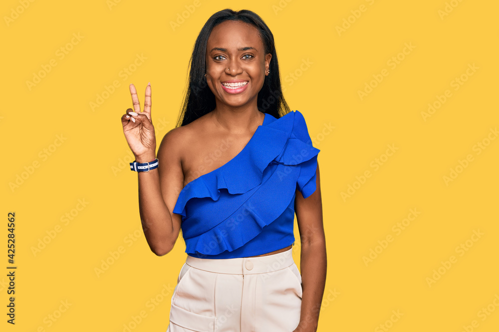 Young black woman wearing casual clothes smiling with happy face winking at the camera doing victory sign. number two. Young black woman wearing casual clothes smiling with happy face winking at the camera doing victory sign. number two.