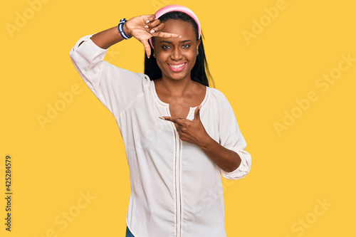Young black woman wearing casual clothes smiling making frame with hands and fingers with happy face. creativity and photography concept.