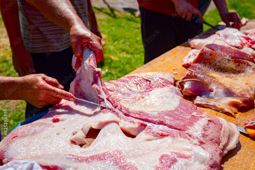 Butcher is cutting, processing fresh meat