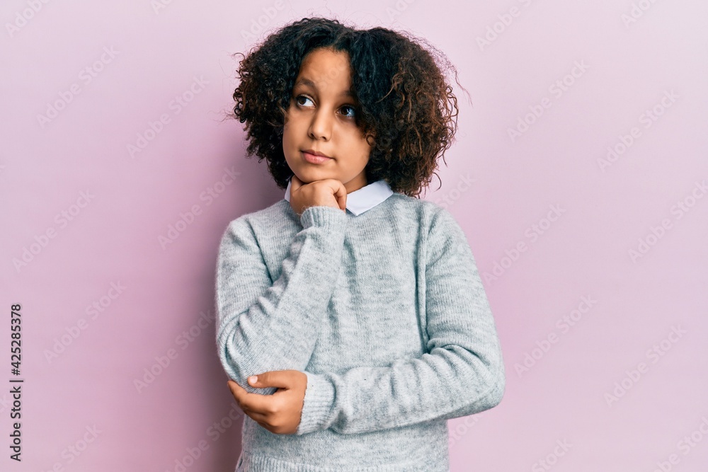 Young little girl with afro hair wearing casual clothes thinking concentrated about doubt with finger on chin and looking up wondering Young little girl with afro hair wearing casual clothes thinking concentrated about doubt with finger on chin and looking up wondering