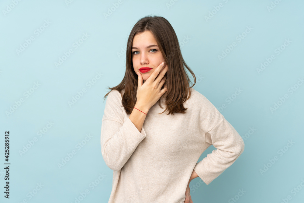 Teenager girl isolated on blue background thinking an idea