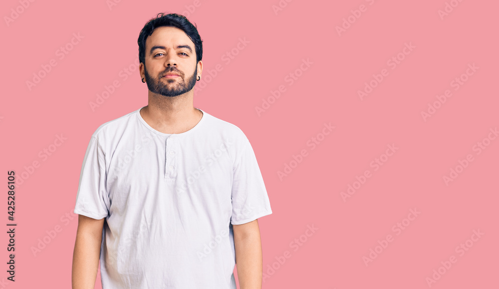 Young hispanic man wearing casual clothes with serious expression on face. simple and natural looking at the camera.