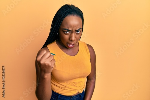 Young african american woman wearing casual clothes angry and mad raising fist frustrated and furious while shouting with anger. rage and aggressive concept.