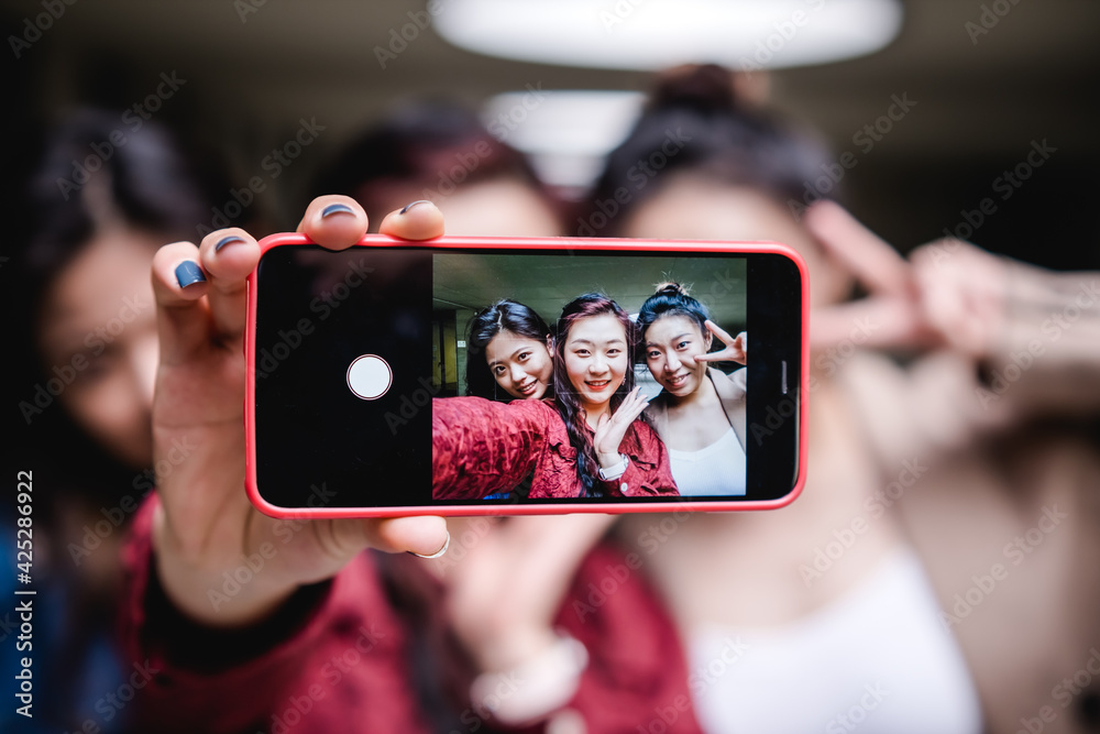 Group of female friends taking a selfie together with a mobile phone. Friendship concept.