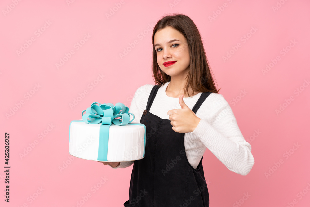 Girl holding a big cake isolated on pink background with thumbs up because something good has happened Girl holding a big cake isolated on pink background with thumbs up because something good has happened